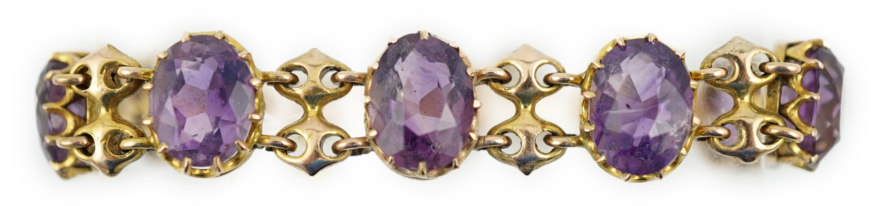 A 9ct gold and graduated seven stone oval cut amethyst set curb link bracelet